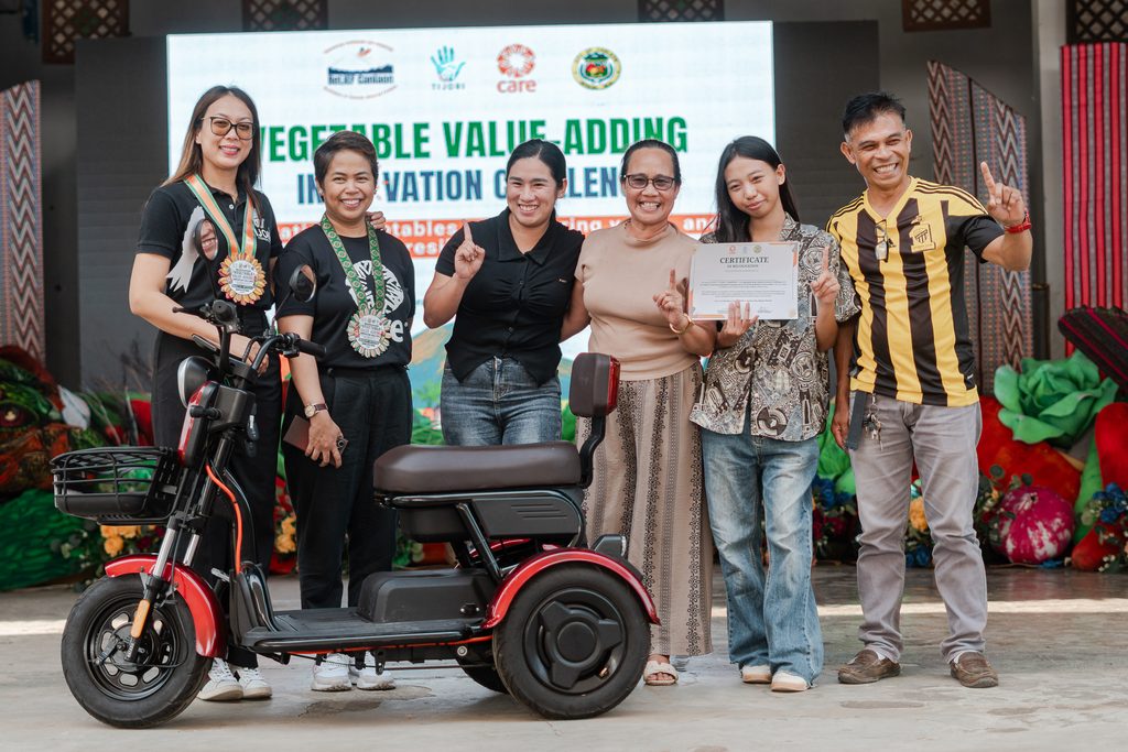 A team accepts a certificate and prize, an e-bike on stage for winning the vegetable innovation challenge.